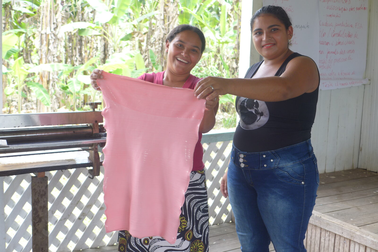 Duas mulheres do grupo erguendo uma manta de FSA recém-prensada